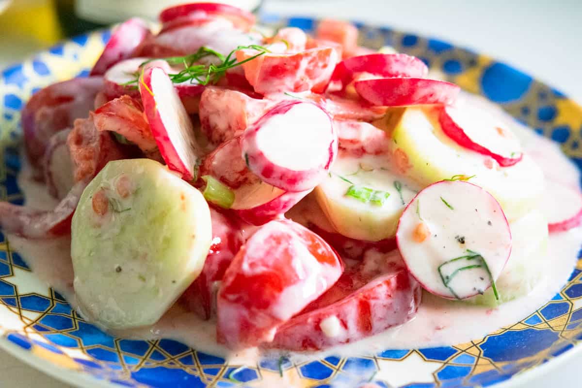 spring radish and tomato salad on a blue and gold plate