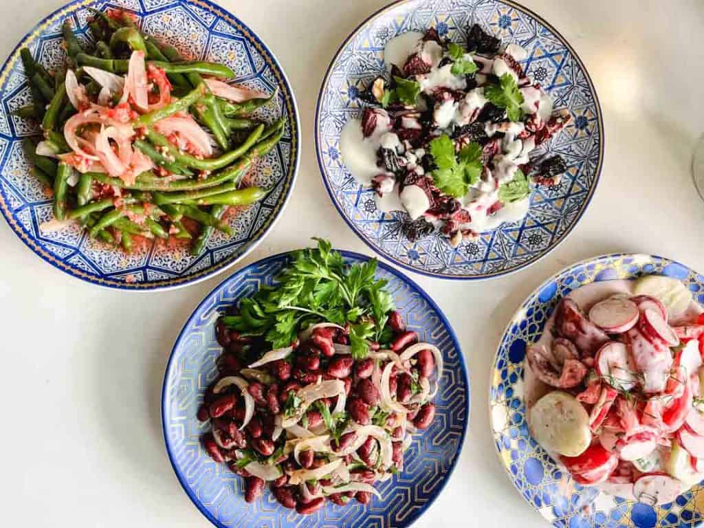 overhead shot of 4 Ukrainian salads on blue and gold round plates