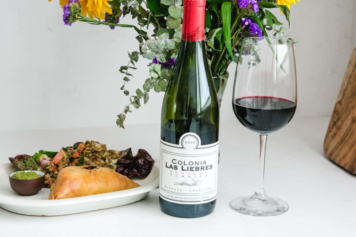 Colonia wine bottle and glass of wine with empanada