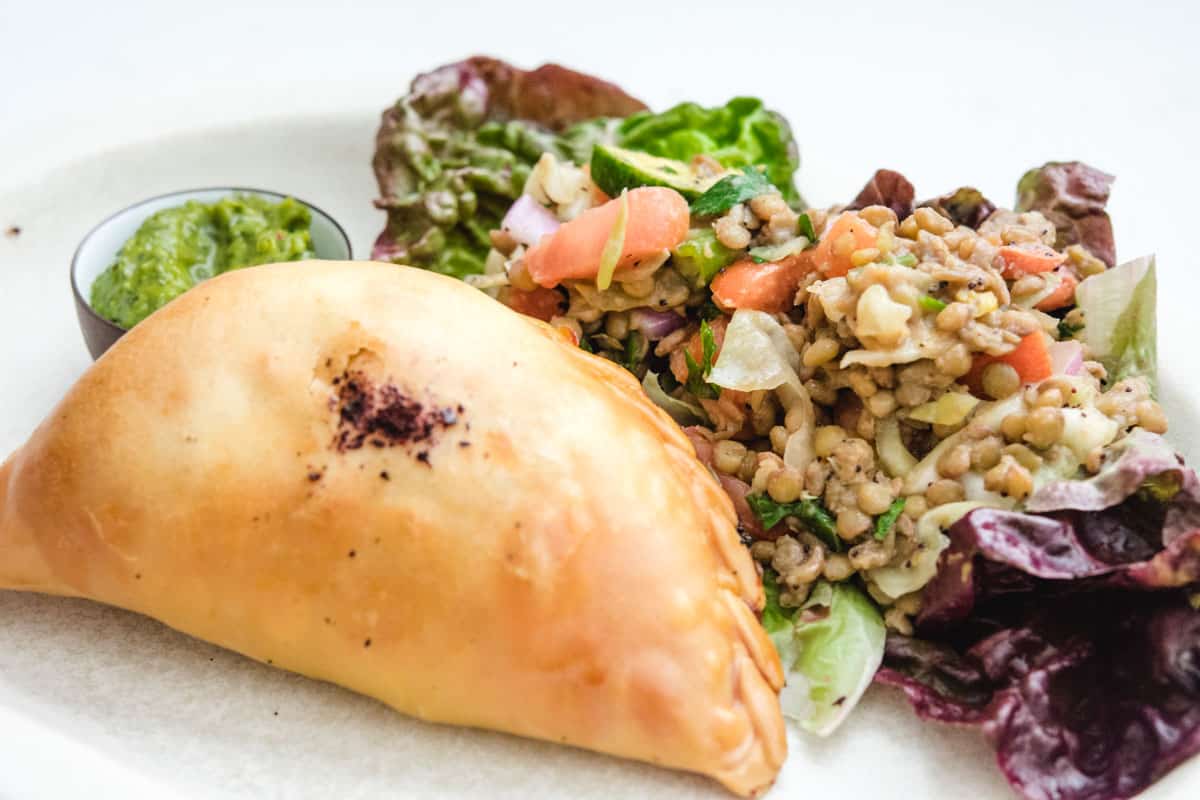 Empanada on a plate with lentil vegetable salad