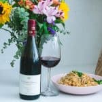 Domaine Carneros Pinot Noir bottle and glass with a pink bowl of pad thai