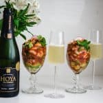 2 glasses of of cava with a wine bottle and 2 goblets of Mexican shrimp cocktail