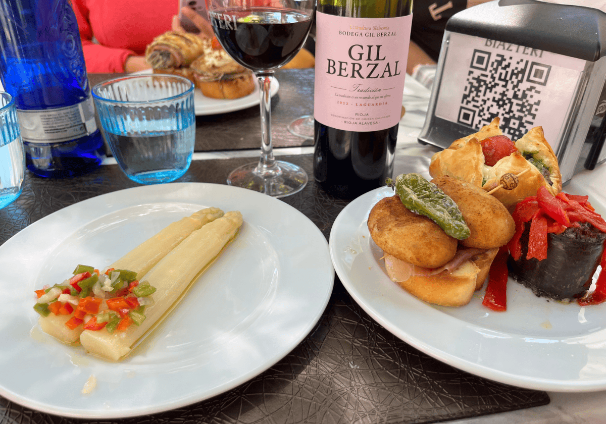2 plates of pintxo appetizers with a glass of red wine in the background